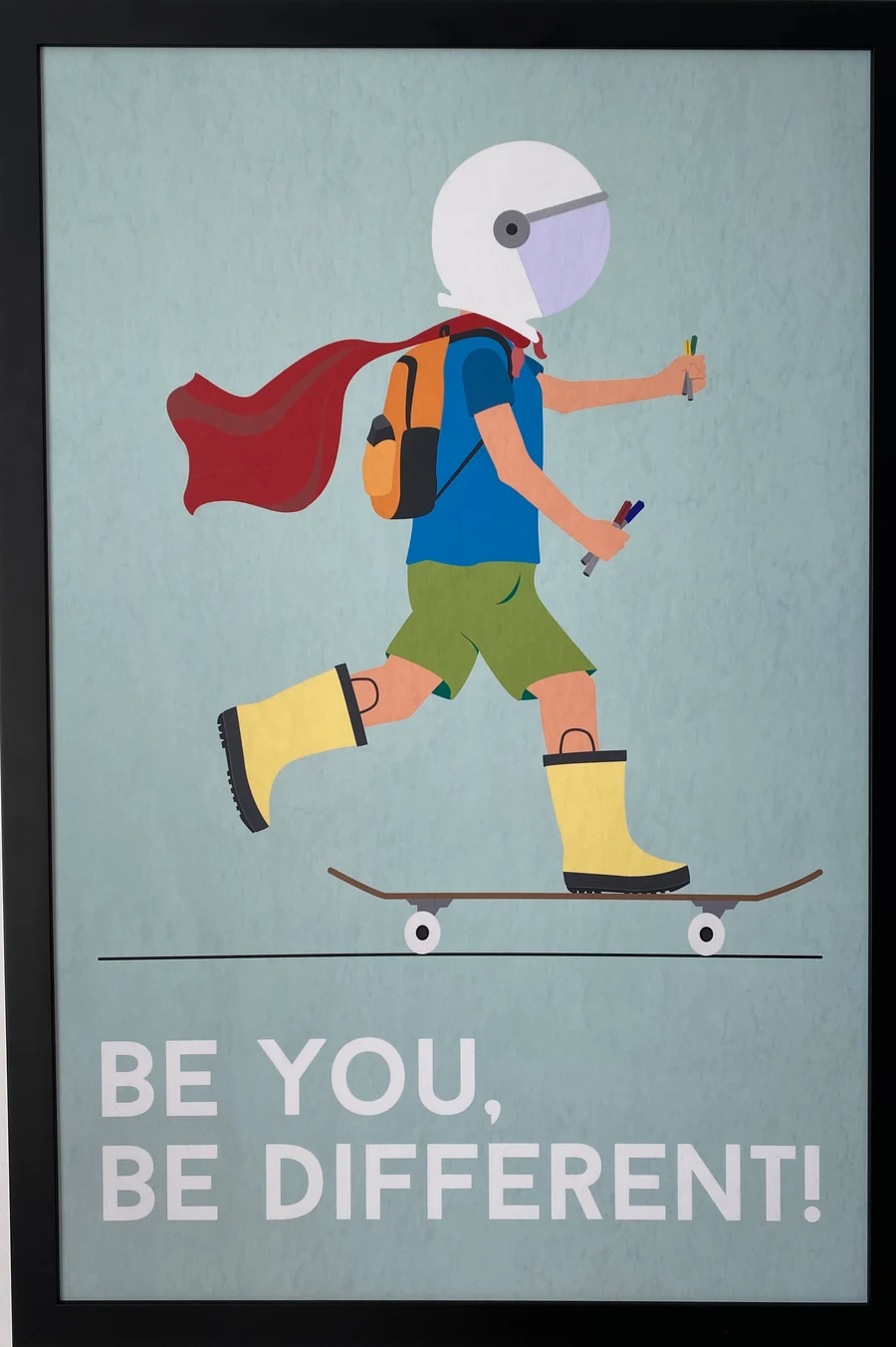 Gerahmtes Plakat an einer Bürowand mit der Aufschrift „Be you, be different!“.